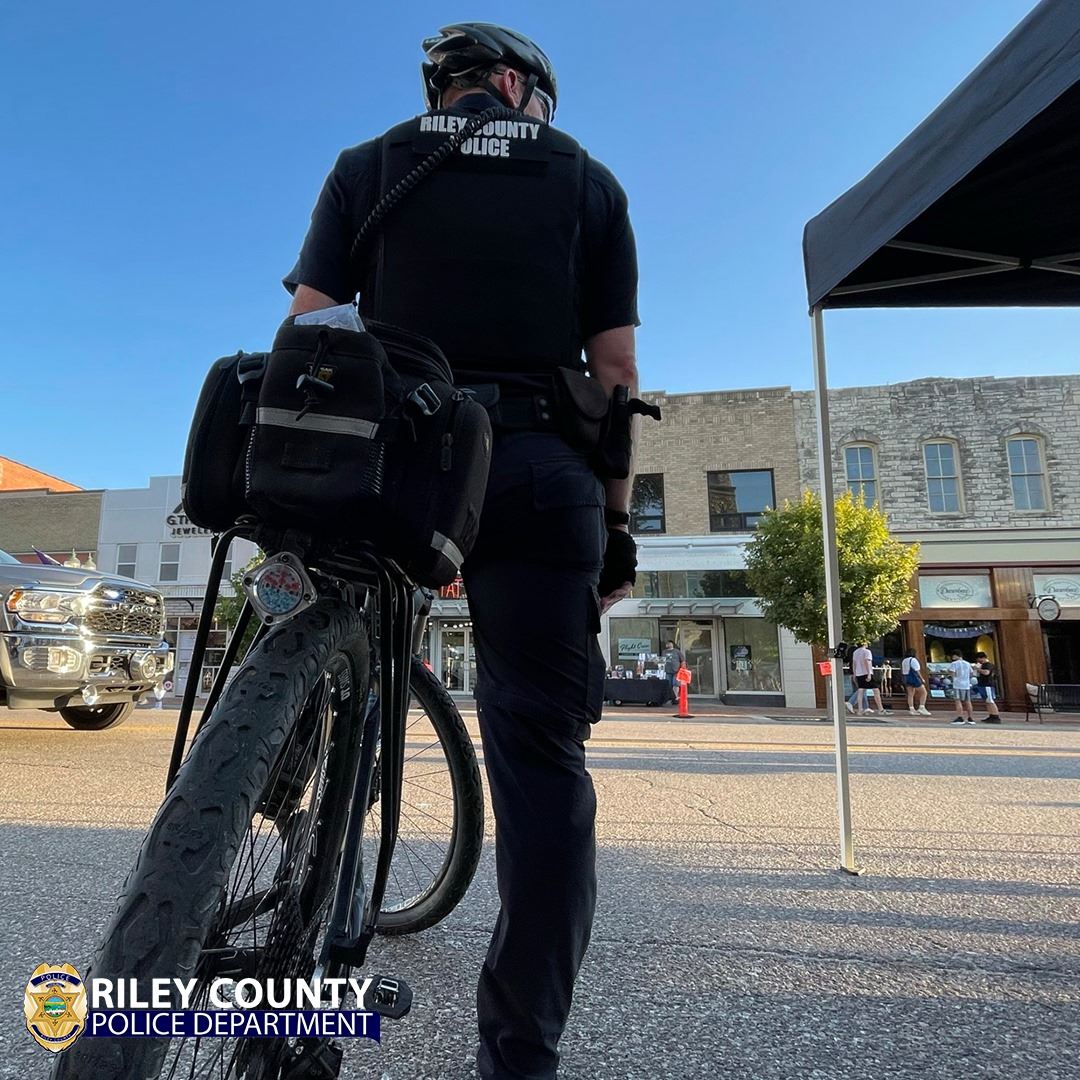 Single Riley County Police Officer on a Bike looking into the street